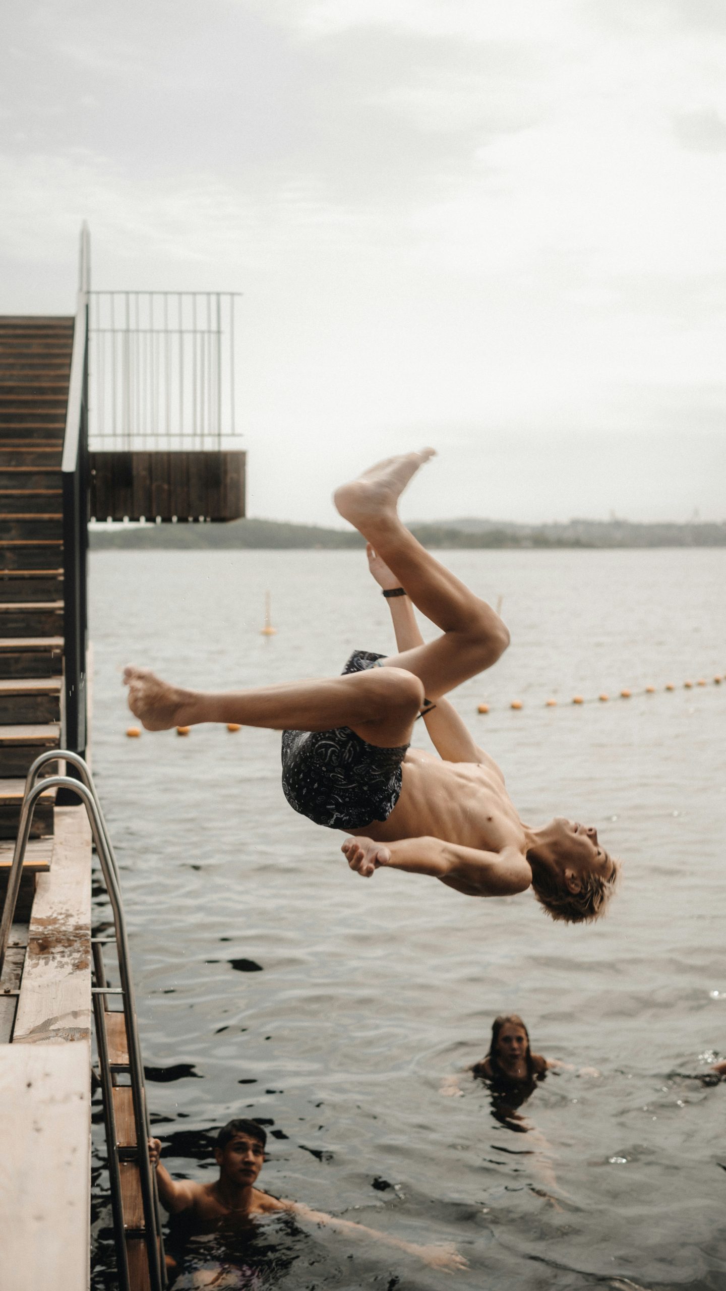 A man performs a backflip into the water.